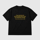 A black short-sleeve crewneck t-shirt with a yellow printed quote on the chest, displayed flat against a light gray background.